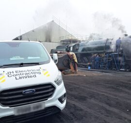 JH Electrical van parked next to a train