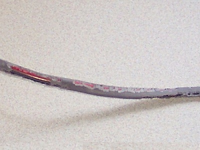 Close-up of damaged electrical cable insulation exposing internal wiring.